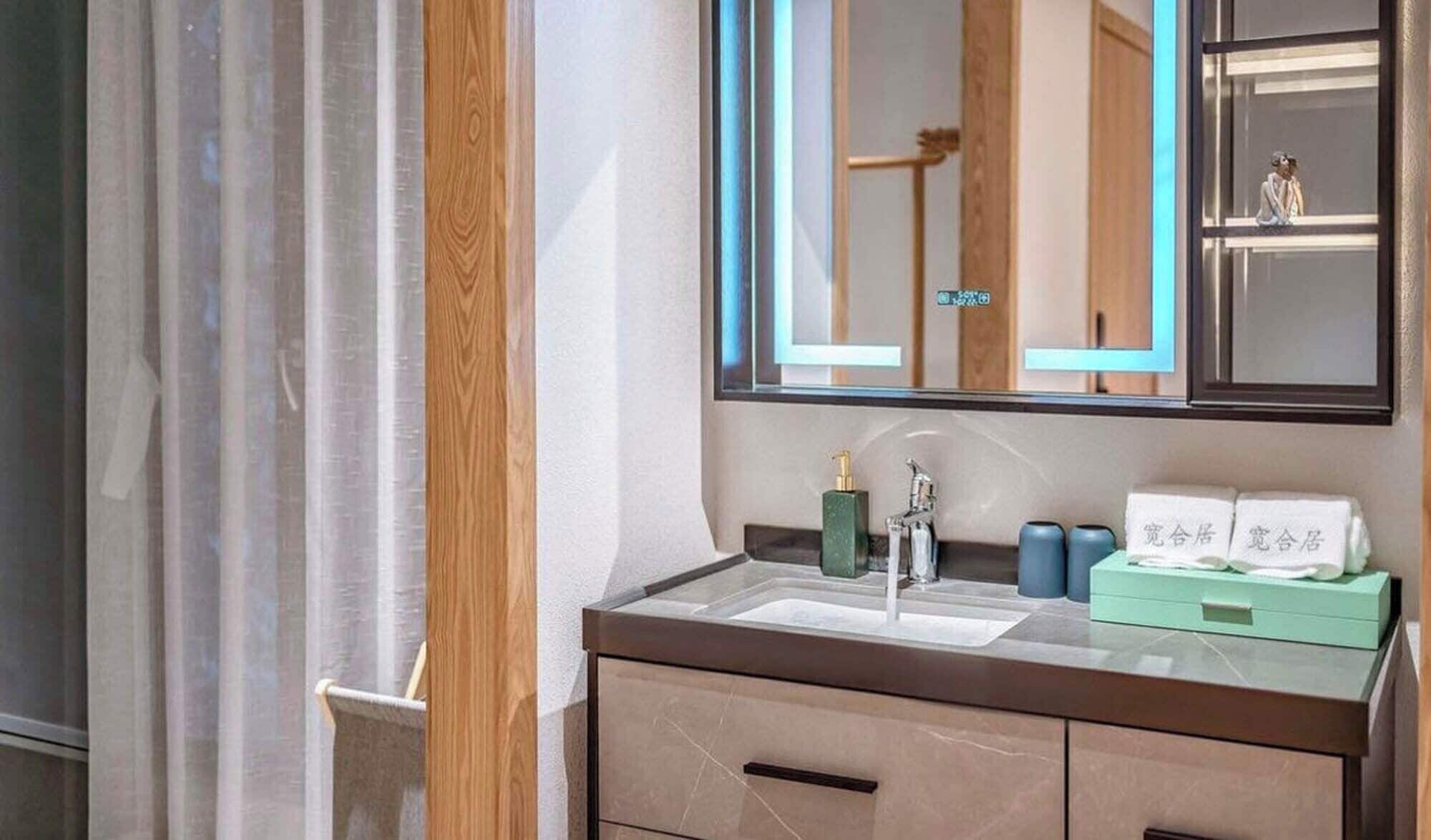 A modern bathroom with a large mirror, a sink, and a vanity with drawers.
