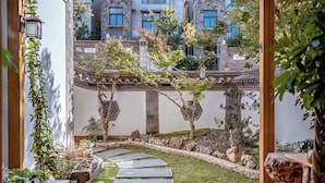 Un patio con un camino de piedra que lleva a una edificación tradicional con techo de tejas.