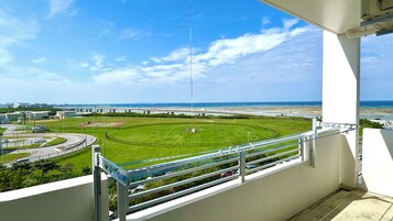 A balcony with a view of a sports field, a bridge, and a coastal area.