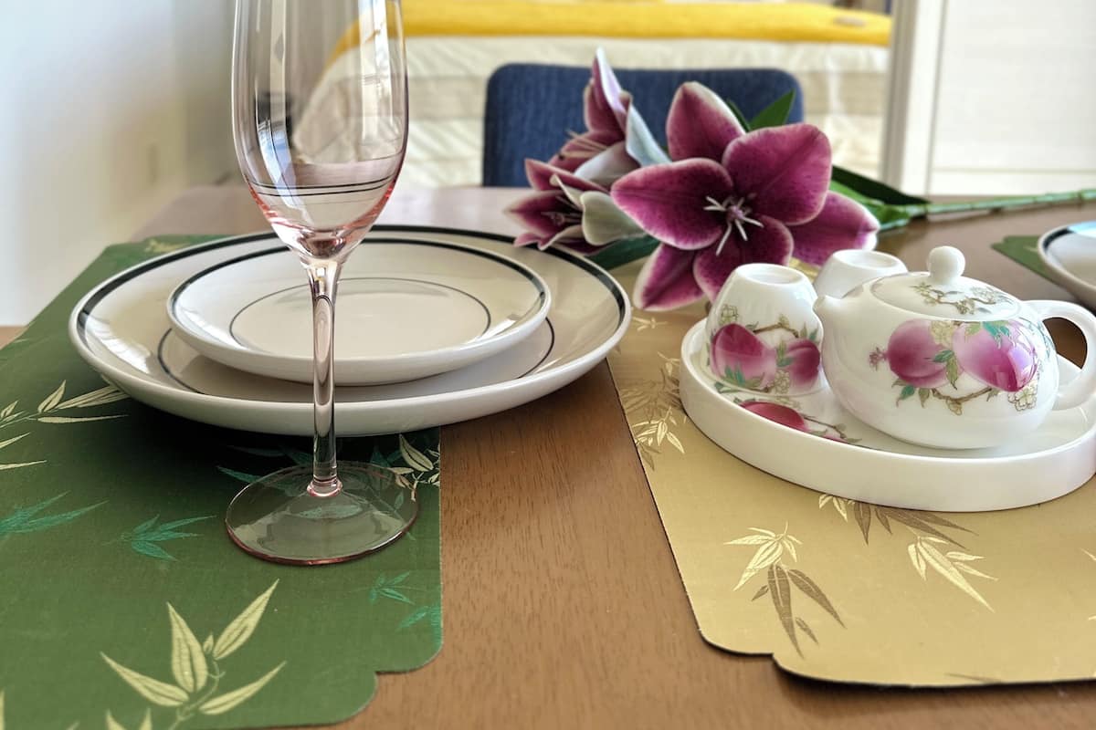 A dining table with a wine glass, plates, and a teapot set.