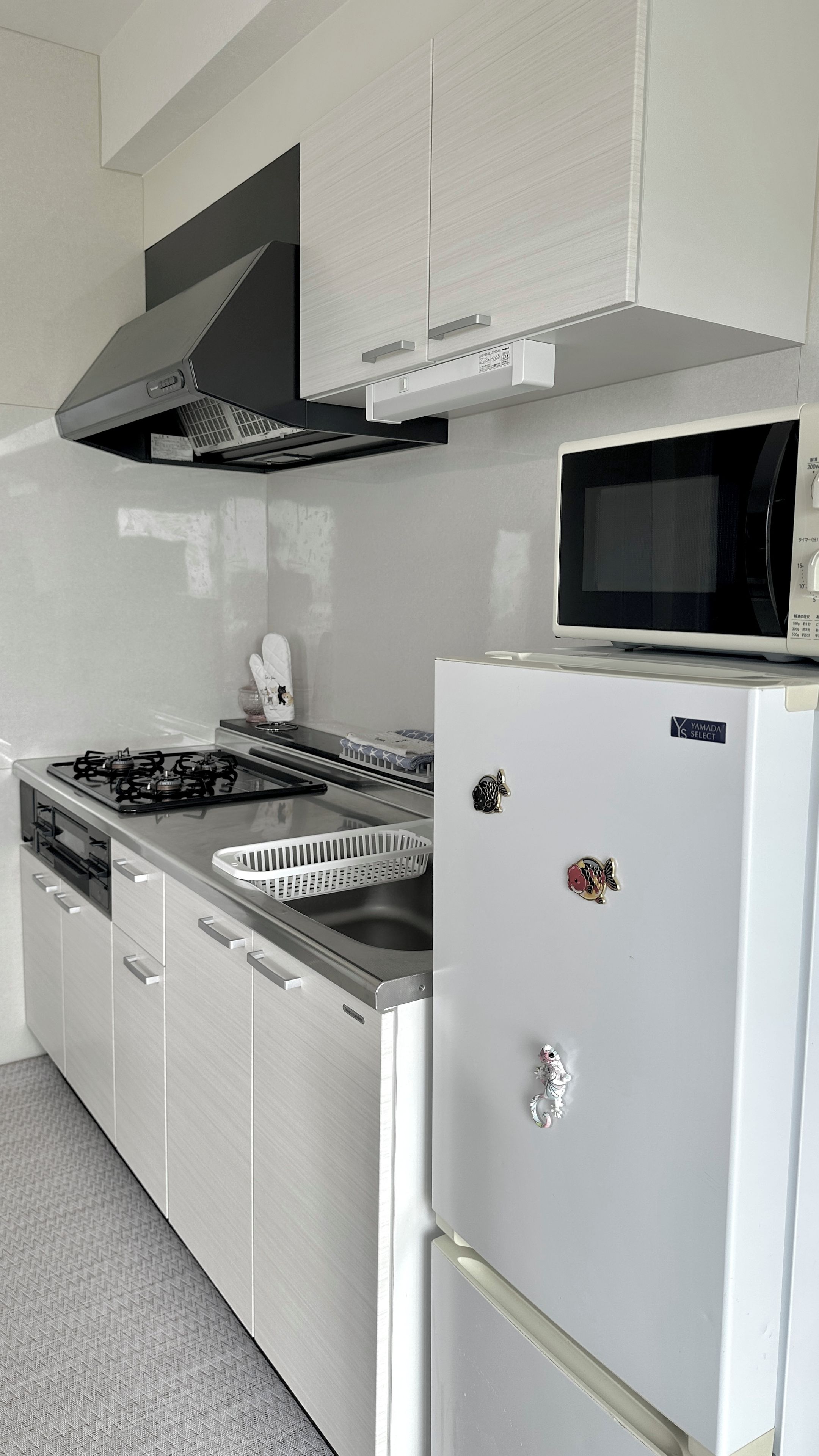 A modern kitchen with a gas stove, microwave, white cabinets, and a stainless steel sink.
