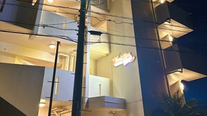 A multi-story building with illuminated balconies and a lit sign reading "Hotel du Vent." - SunSea Okinawa Stunning Ocean View 2BR Sleeps 6 20 min from Airport 3 min to Shopping Mall (Urasoe)