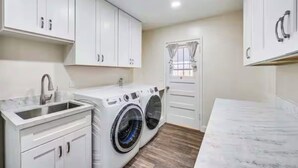 A laundry room with a washing machine, a sink, and cabinets. - Pet-Friendly Home • Yard + Deck • Minutes to DT SD (Lemon Grove)