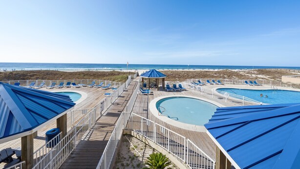 A beachside resort with multiple swimming pools, lounge chairs, and a gazebo. - Sugar Beach 313 (Orange Beach)