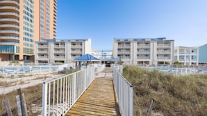 A boardwalk leading to a beachfront hotel with multiple balconies and a pool area. - Sugar Beach 313 (Orange Beach)