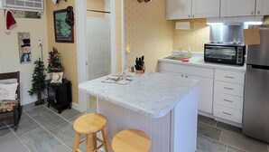 Een keuken met een marmeren eiland, witte kasten, een roestvrijstalen koelkast en een zwarte oven.