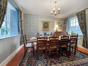 A dining room with a large table set for six, surrounded by wooden chairs, a chandelier, and patterned rugs. - 5 bedroom accommodation in Church Stretton (Church Stretton)