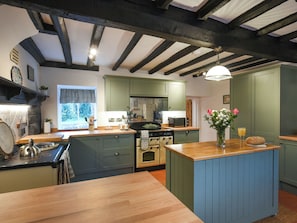 A kitchen with green cabinets, a wooden countertop, a stove, and a sink. - 5 bedroom accommodation in Church Stretton (Church Stretton)
