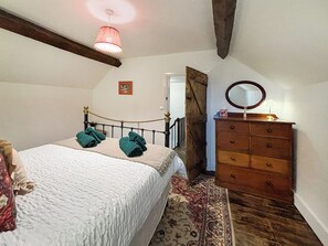 A bedroom with a bed, a dresser, a mirror, a hanging light fixture, a door, and a patterned rug. - 5 bedroom accommodation in Church Stretton (Church Stretton)