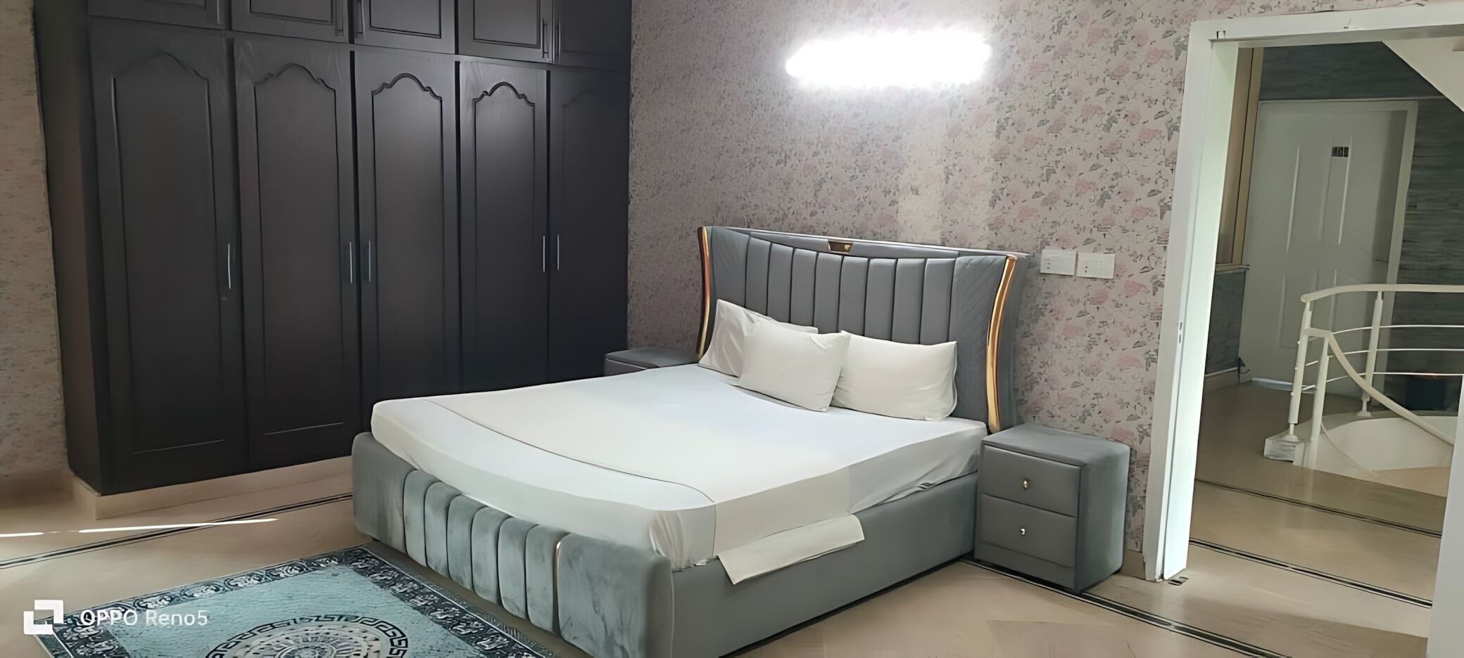 Une chambre à coucher comprenant un lit, une table de chevet, une armoire et une salle de bain avec douche.