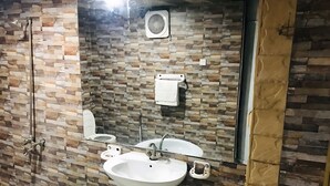 A bathroom with a tiled wall, a sink, a mirror, and a shower. - Sapphire Lodge (Islamabad)