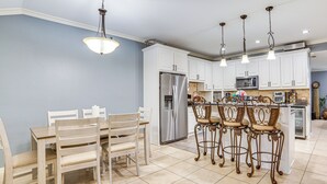 A modern kitchen with white cabinets, stainless steel appliances, and a central island with bar stools. - Dallas Area Home w/ Hot Tub, Families Welcome! (Duncanville)