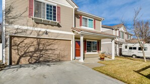 Une maison à deux étages avec un garage, une véranda et une petite allée.