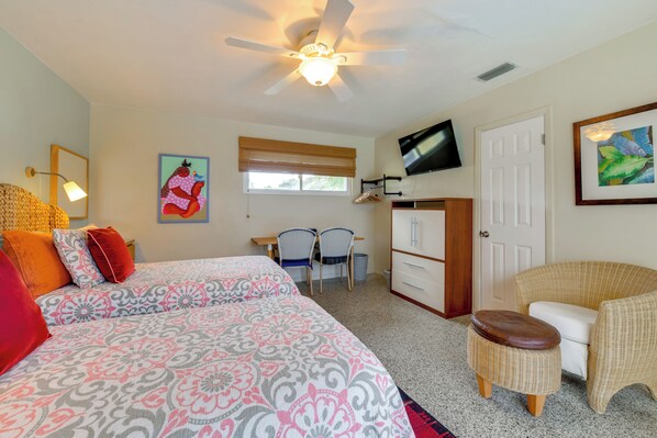 A bedroom with two beds, a ceiling fan, a TV, a desk with chairs, and a wicker chair. - 4 Mi to Siesta Key Beach! Home w/ Backyard Oasis (Sarasota)