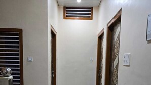 A hallway with a 'WELCOME' mat, a ceiling vent, and a door with decorative paneling. - Hotel Anmol Kothi (Ayodhya)
