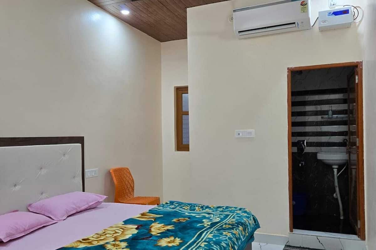 Un dormitorio con cama, ventilador de techo, equipo de aire acondicionado y ventana con vistas al exterior.