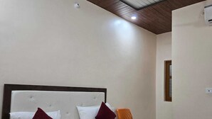 A hotel room with a bed, a ceiling fan, and a window. - Hotel Anmol Kothi (Ayodhya)