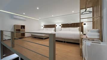 A modern hotel room with two beds, a wooden wardrobe, a hanging coat rack, and a small seating area with a table.