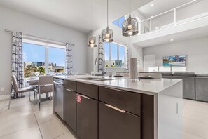A modern kitchen with a large island, stainless steel appliances, and pendant lighting. - 7740 Sandy Ridge Drive Unit 3-214 (Kissimmee)