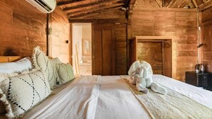 Une pièce en bois avec un lit, des oreillers et une petite table sur laquelle se trouve une bouilloire.