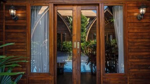 Une cabane en bois dotée d’une porte-fenêtre coulissante qui donne sur un espace extérieur couvert avec une piscine.