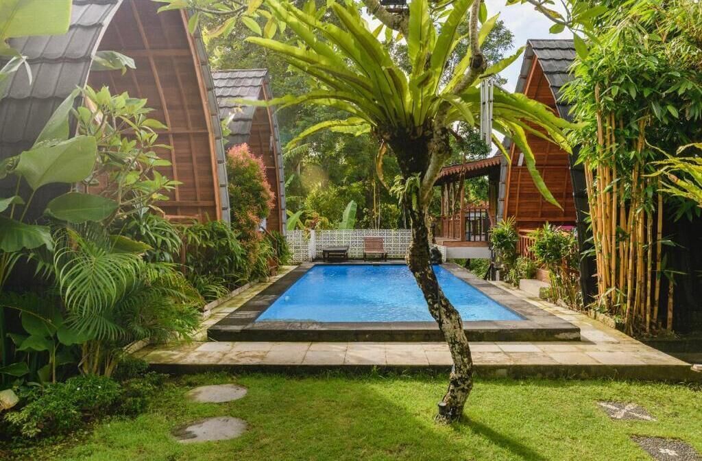 A swimming pool surrounded by lush greenery and wooden structures.