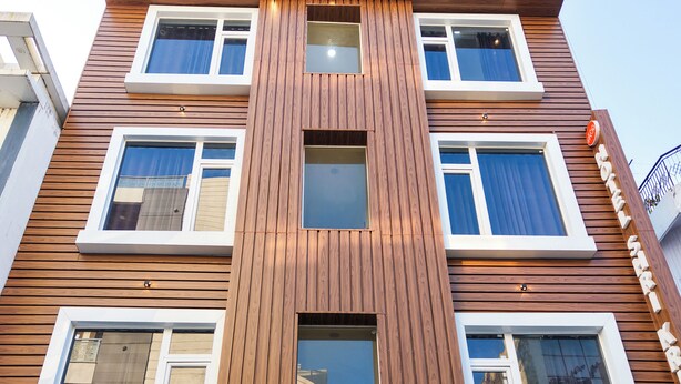 Ein mehrgeschossiges Gebäude mit Holzfassade und zahlreichen Fenstern. Am Eingang ist die Schrifttafel "The Hofte VIBRANTA" sichtbar.