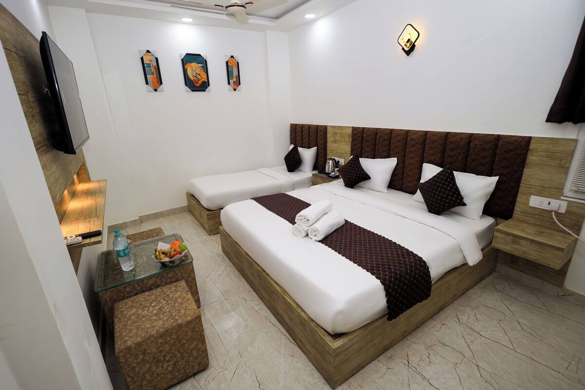A hotel room with a large bed, two bedside tables, a flat-screen TV, and artwork on the walls.