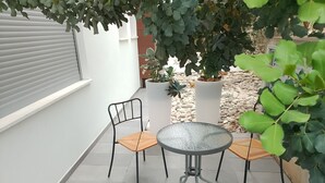 An outdoor patio with a round table and two chairs, surrounded by potted plants and a stone wall. - The studio offers cleanliness, peace and comfort, for a pleasant, relaxing stay! (Pafos)