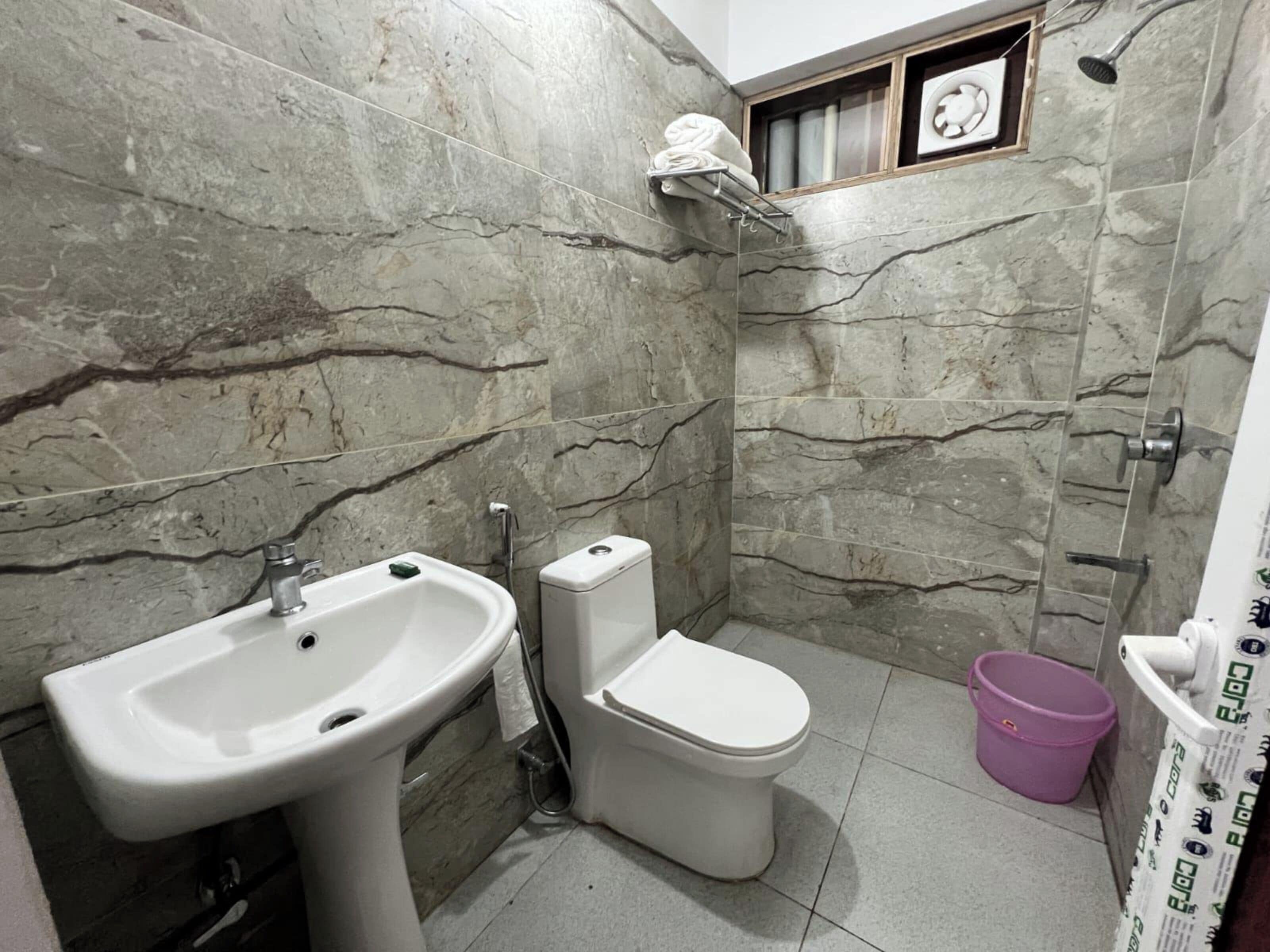 Ein Badezimmer mit Waschbecken, Toilette, Dusche und einem kleinen Fenster.