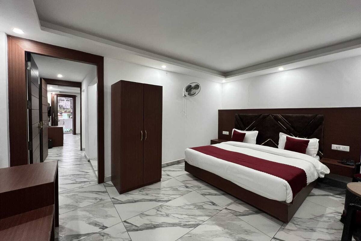 Een hotelkamer met een groot bed, een kledingkast, een bureau en een ventilator.
