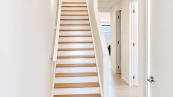 A staircase with wooden steps leading to a landing, surrounded by white walls and doors.