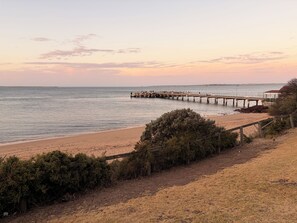 A beach with a wooden pier extending into the water, surrounded by dry grass and bushes. - Cowes Family Retreat | Walk to beach, shops & cafes - Sleeps up to 14 (Cowes)