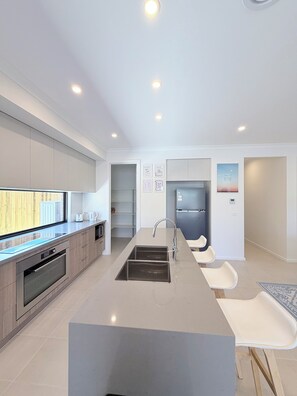 A modern kitchen with a central island, stainless steel appliances, and a built-in oven. - Cowes Family Retreat | Walk to beach, shops & cafes - Sleeps up to 14 (Cowes)