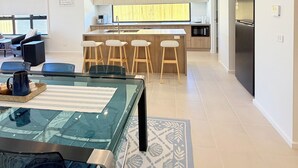 Eine moderne Küche mit Kochinsel, Barhocker und Kühlschrank.