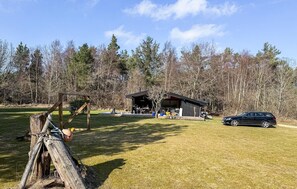 A rustic cabin with a covered outdoor seating area, surrounded by a forest. - 4 bedroom beautiful home in ålbæk (Ålbæk)