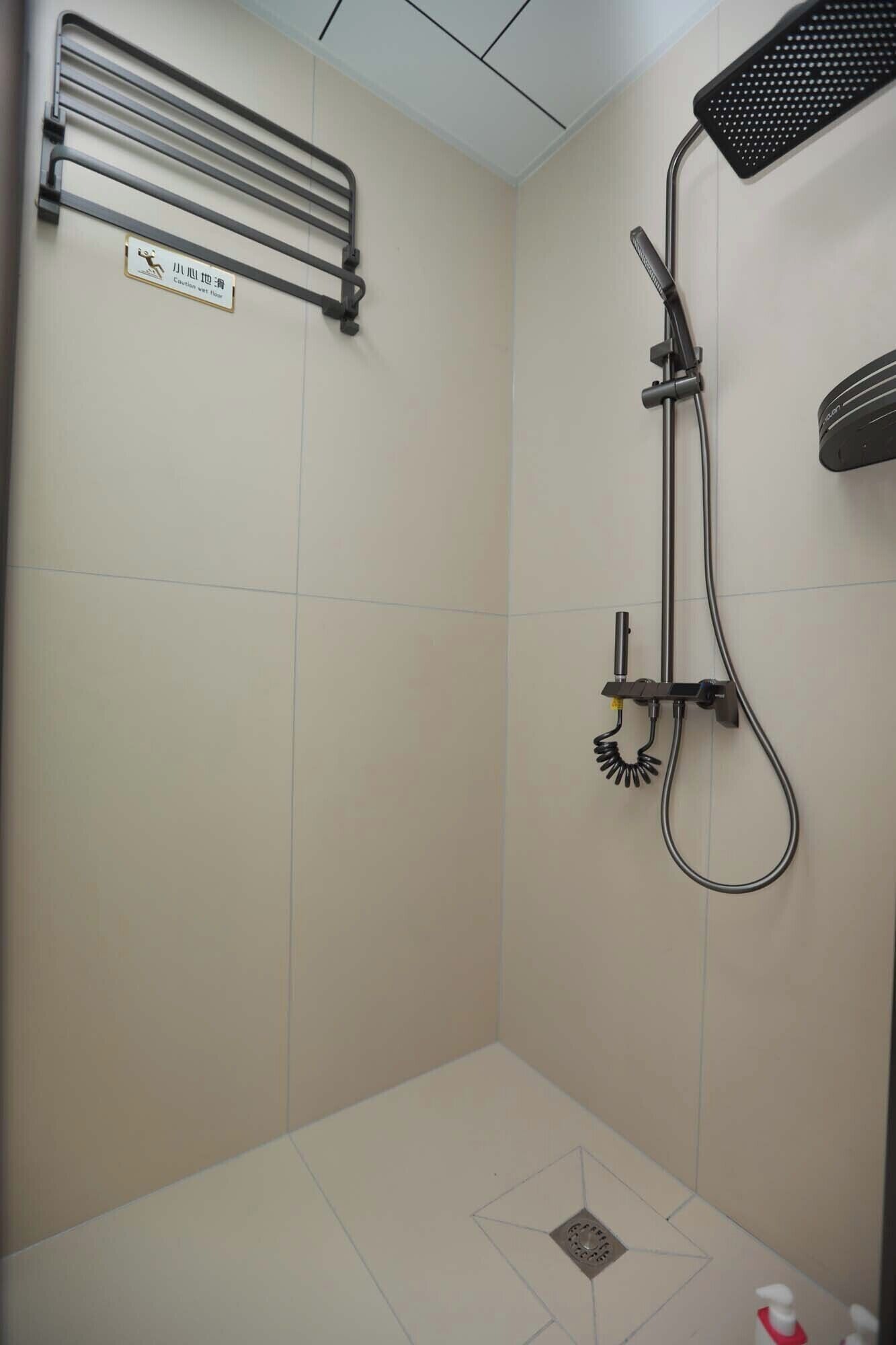 Un baño pequeño con azulejos, cabezal de ducha de mano, toallero en la pared y un organizador para el baño.