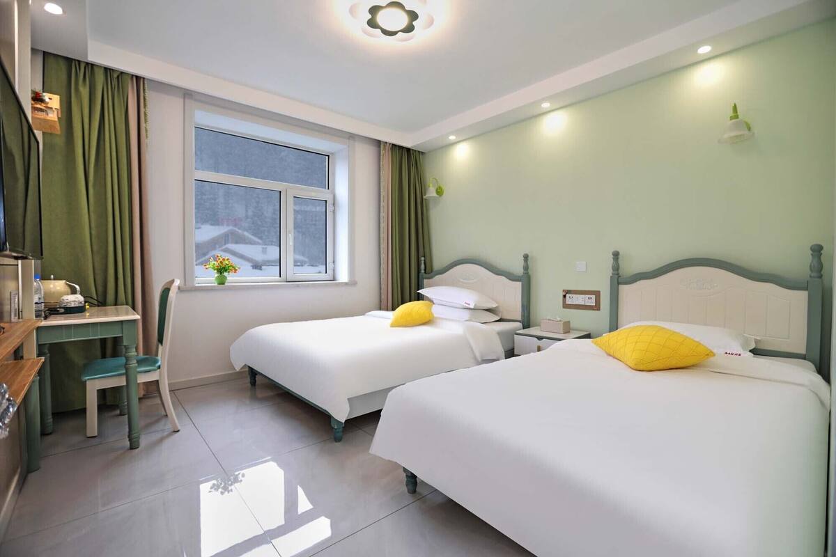Een hotelkamer met twee bedden, een bureau en een raam.