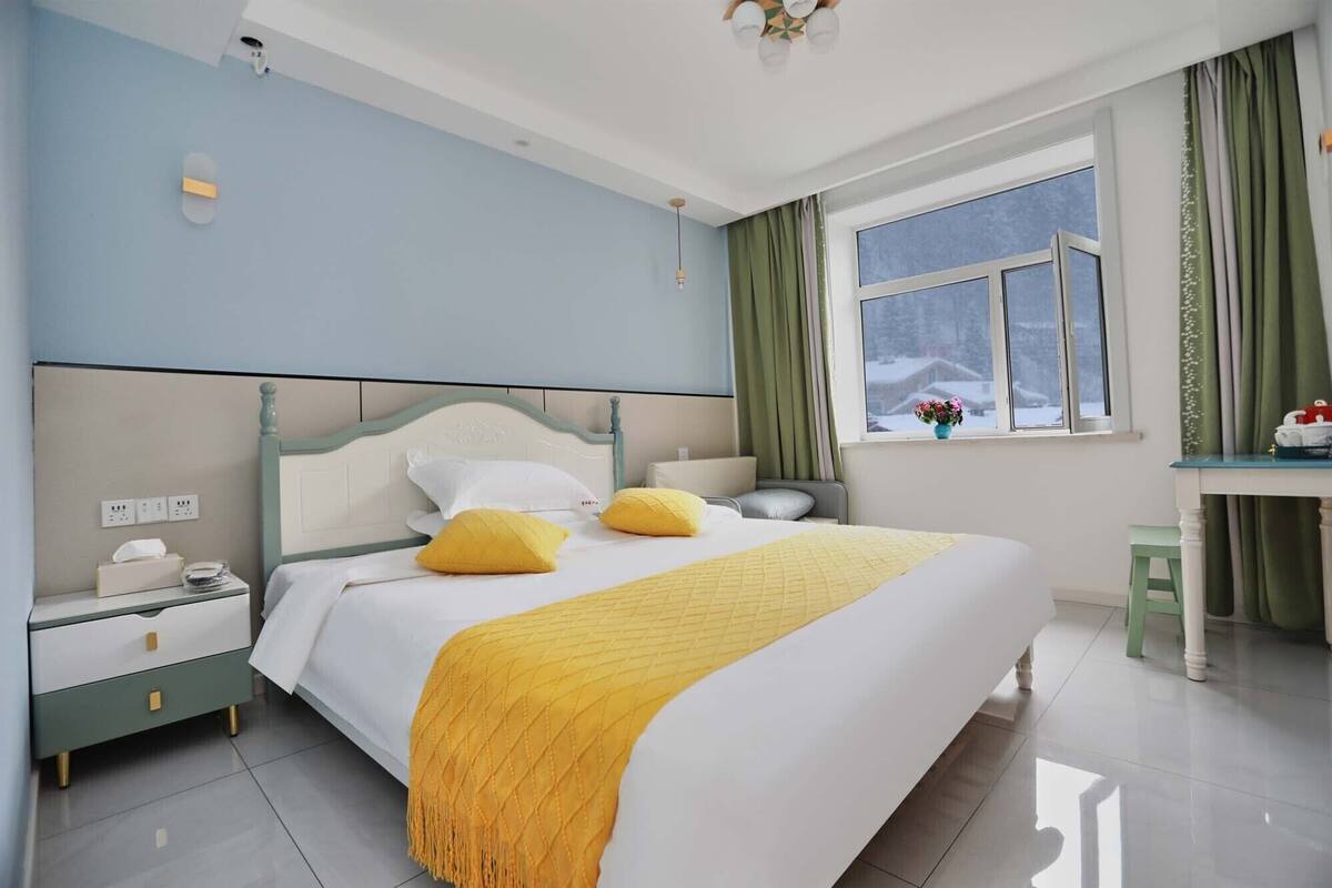 Een moderne slaapkamer met een bed, nachtkastjes, een raam met gordijnen en uitzicht op de omgeving.