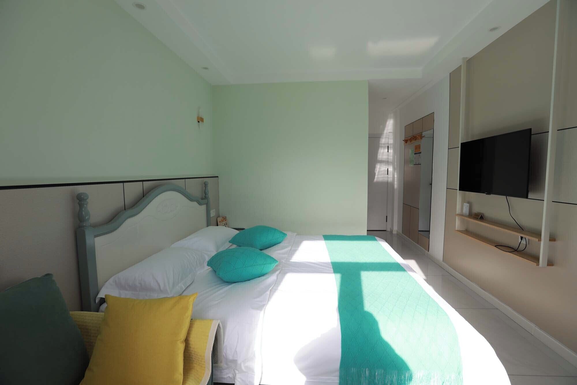 A bedroom with a bed, pillows, a TV, and a bathroom in the background.
