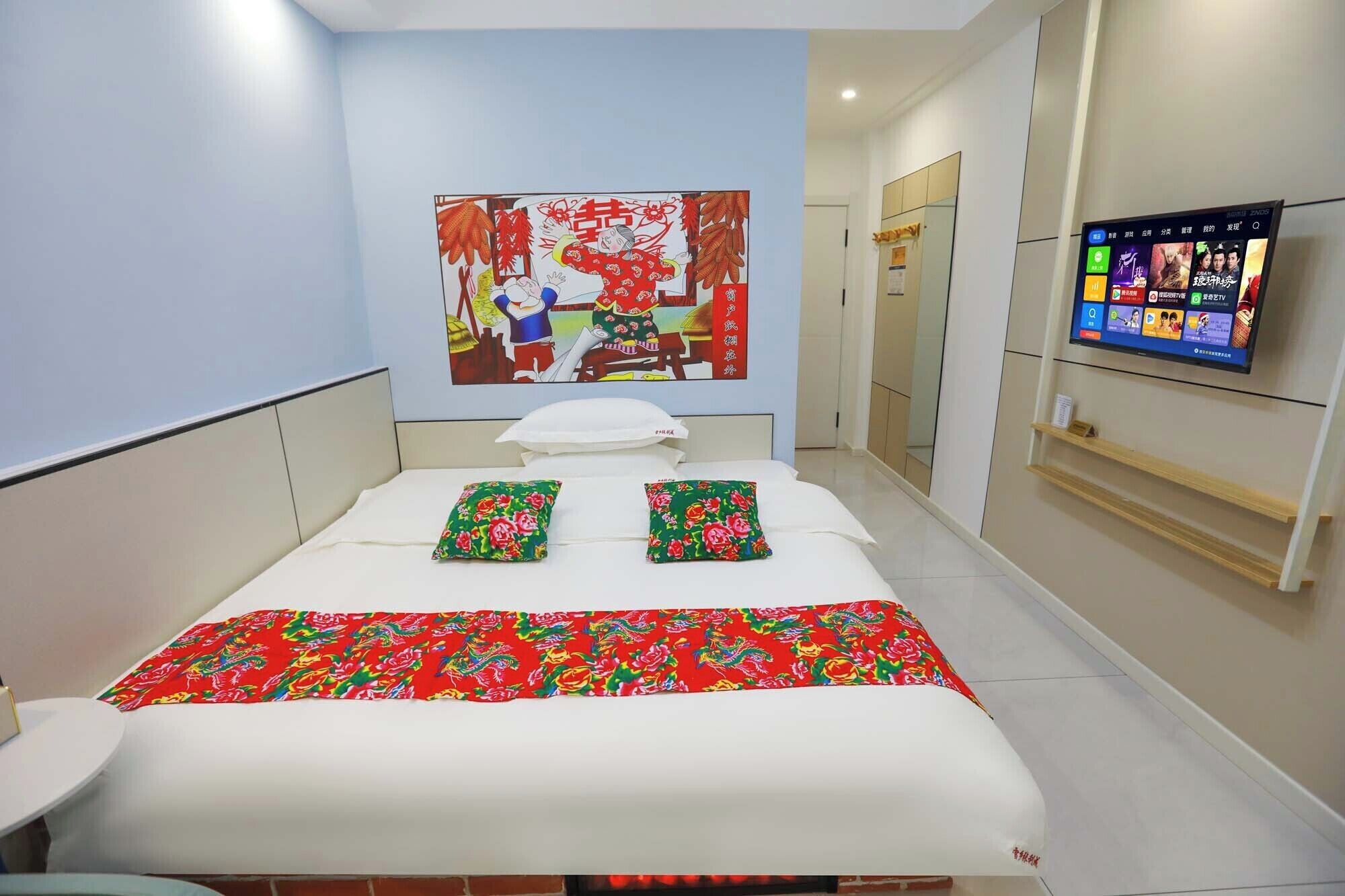 A hotel room with a bed, pillows, a TV, and a wall decoration.