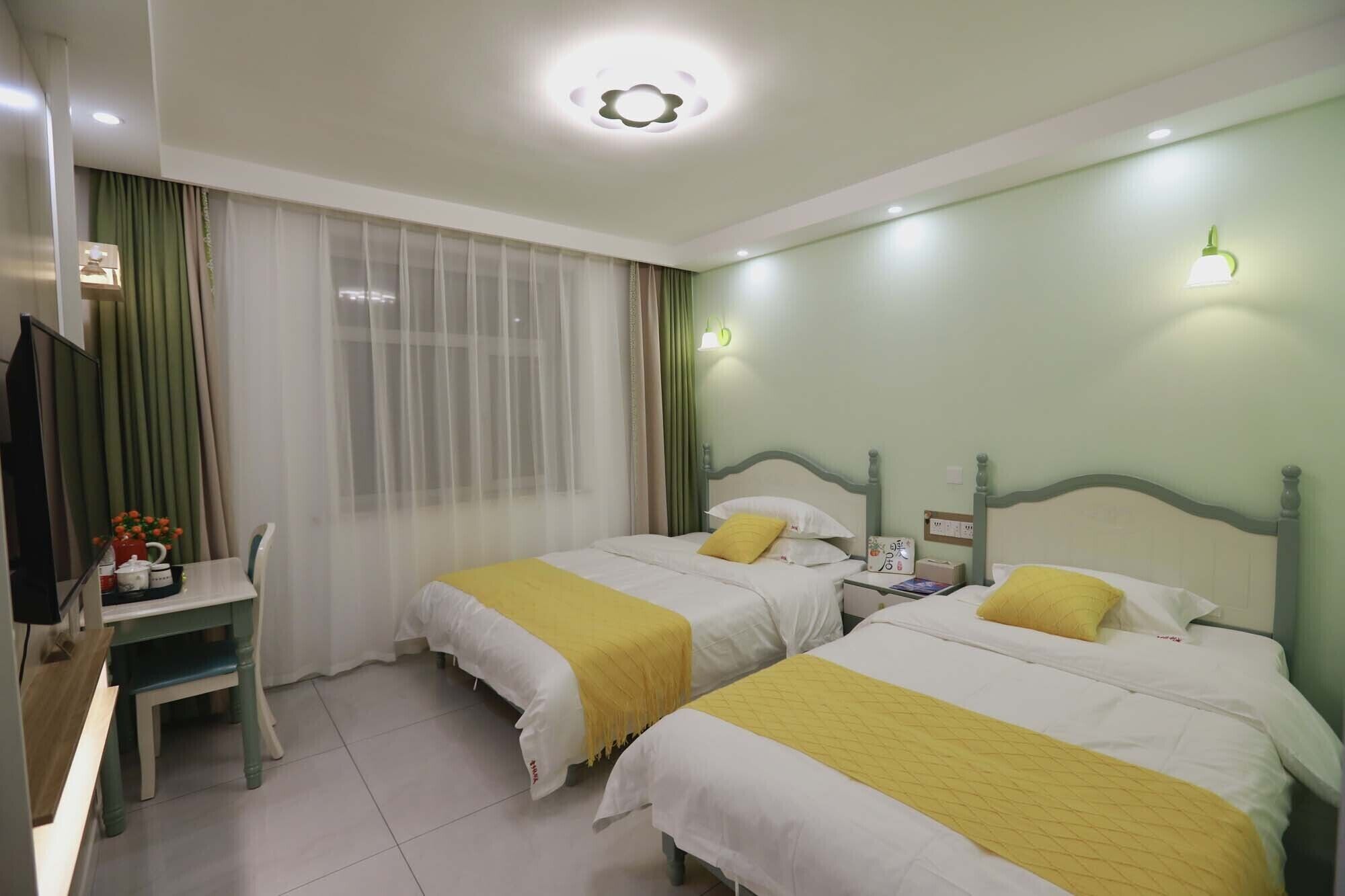 A hotel room with two beds, a desk, and a TV.