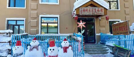 A hotel entrance with a snowman decoration and a blue fence.