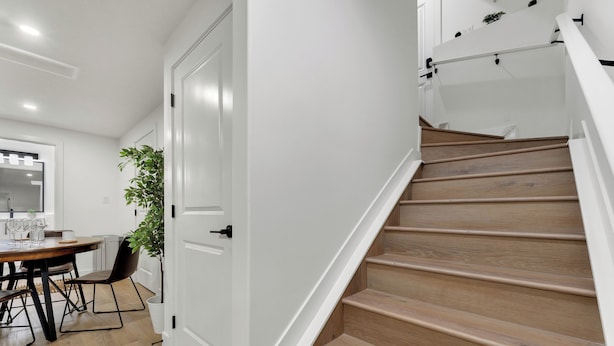 A staircase with wooden steps and white walls, leading to a room with a dining table and chairs. - 2 bedroom suite with 3 beds, close to Amenities and Airport (Leduc)