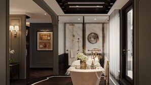 A modern bathroom with a freestanding bathtub, a vanity with a gold faucet, and a large window providing natural light. - Aime'e Luxury Cruise (Bai Chay)