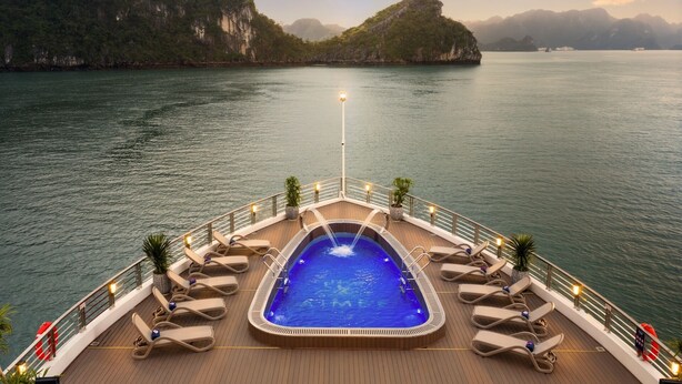 A cruise ship deck with a hot tub surrounded by lounge chairs, overlooking a calm sea with distant islands. - Aime'e Luxury Cruise (Bai Chay)