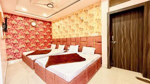 A double bed with a headboard, a clock on the wall, and a door to the right. - Premium Hotel Sipra near Mahakal Temple  (Ujjain)