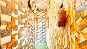 A narrow hallway with patterned walls and a green carpet. - Premium Hotel Sipra near Mahakal Temple  (Ujjain)