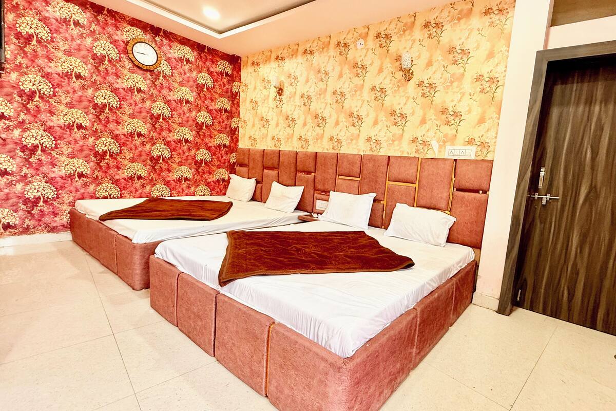 A hotel room with two beds, a large clock on the wall, and a door.