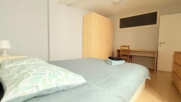 Een slaapkamer met een bed, een bureau, een stoel en een kledingkast.